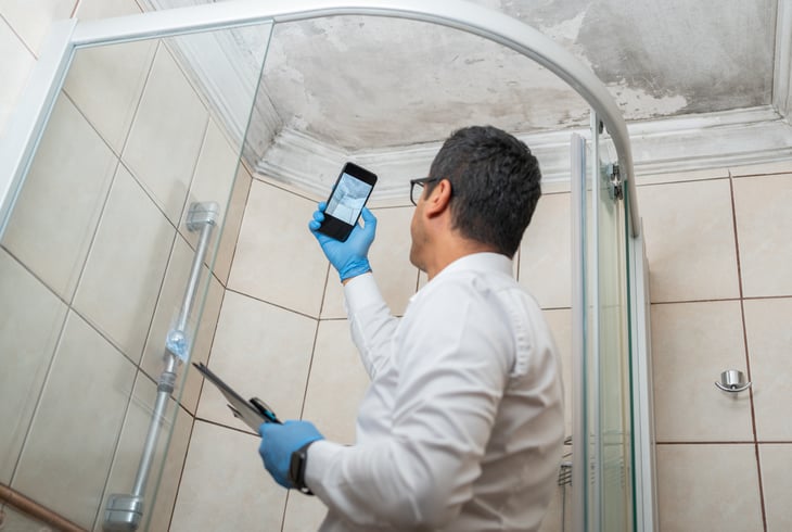 Guy Taking Pictures By Smartphone Of Bathroom Ceiling Damage