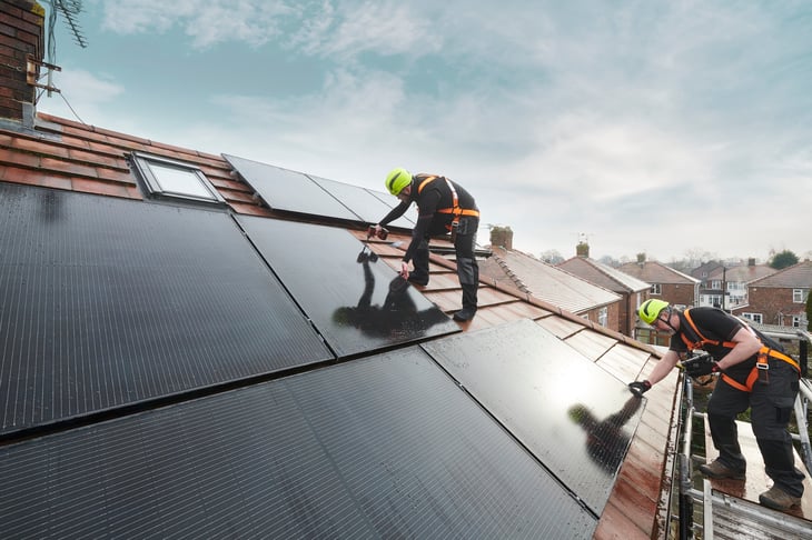 Istock image of guys laying solar panels on a house roof