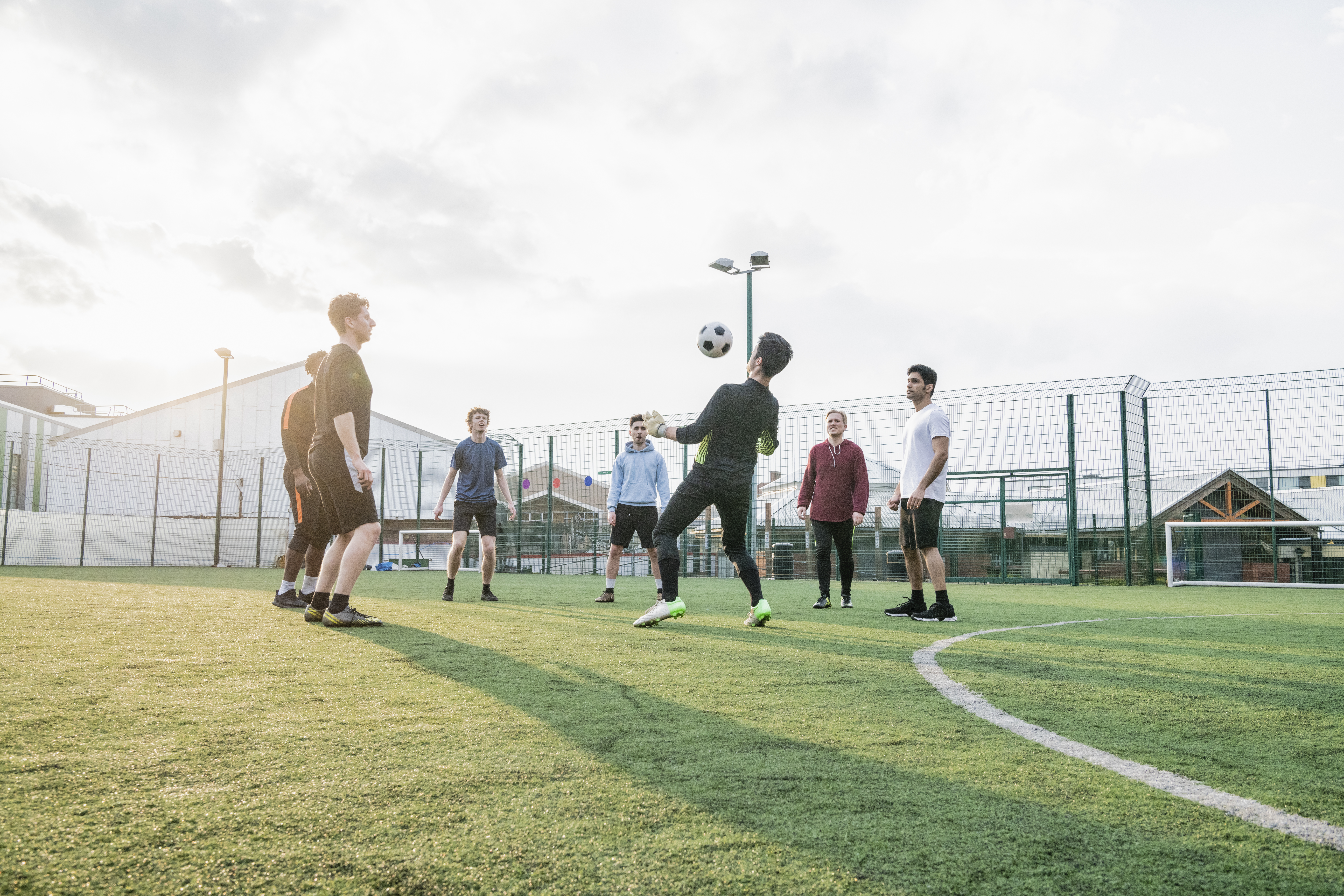 Group of boys playing football on sports pitch